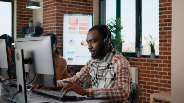 istock Young man using headphones at call center to help people 1447093220
