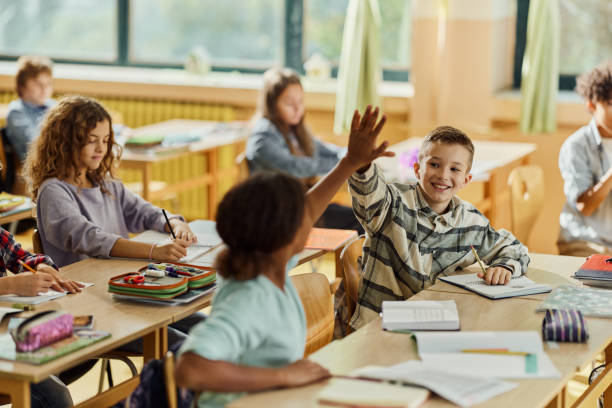 istock Happy students giving each other high-five on a class at school. 1447093396