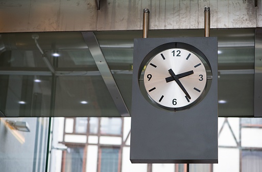 A modern wall clock hanging close to the ceiling