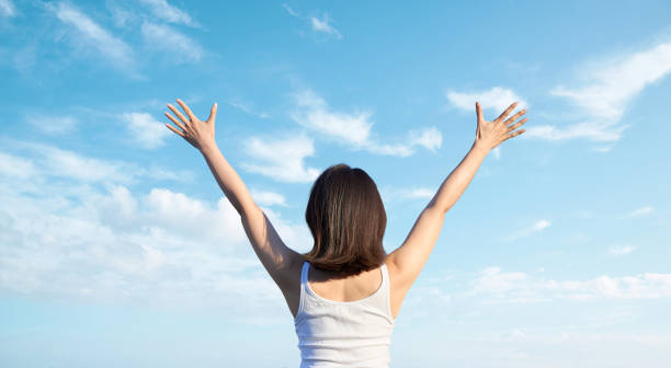 青空に手を上げるアジア人女性 - body conscious ストックフォトと画像