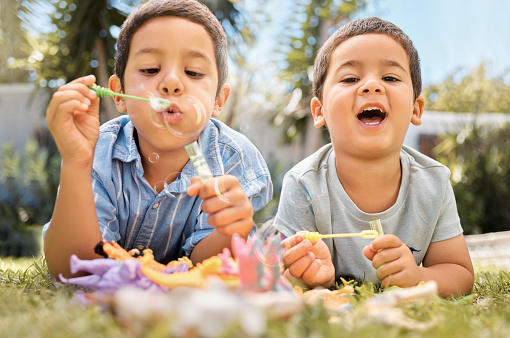 Brothers kids blowing bubbles in park, garden and backyard, grass and nature fun, joy and happy youth development, growth and relax. Young brothers, happy children playing game and soap bubbles