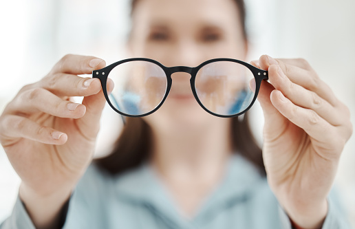 Eyes, vision and glasses with the hands of a woman optometrist holding spectacles during an eye test or exam. Frame, medical and insurance with a female optician showing prescription eyewear