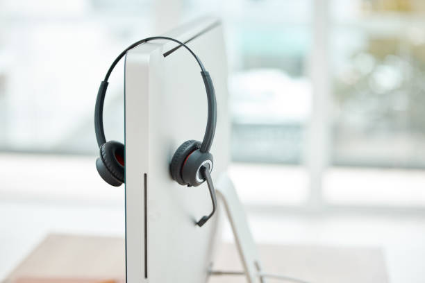 istock Headphone, contact us and empty office at call center with computer for online customer service or support. Helpdesk hotline assistance gadgets and crm equipment in workplace or telemarketing office 1447101699