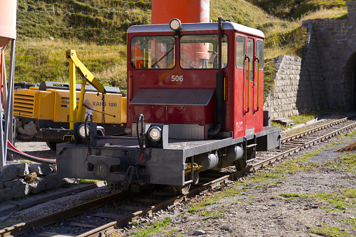 Red shunting locomotive of historic narrow gauge railway at portal of tunnel at Swiss mountain pass Furkapass on a sunny late summer day. Photo taken September 12th, 2022, Furka Pass, Switzerland.