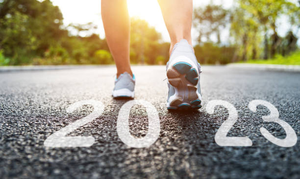 Woman with running shoes standing with new year number 2023 on road stock photo