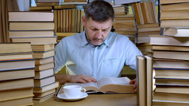 istock A bearded man reads a book in the library 1447105299