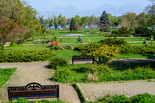 Landscape with old blue house and many large old green trees trees on the shoreline of Herastrau Lake in King Michael I Park in Bucharest, Romania, in a sunny spring day with blue sky