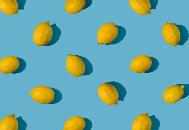 istock Summer pattern made with fresh yellow whole lemons on vibrant light blue background. Minimal background summer concept on bright sunlight with sharp shadows 1447106452