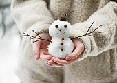 Little cute smiling snowman in the child hands. Having fun in wintertime.