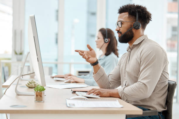 schwarzer mann, kundendienstbüro und arbeit für online-call-center-internet-telemarketing-geschäft. crm-berater am schreibtisch, unterstützt kunden und berät computersoftware - business two people talking building exterior stock-fotos und bilder