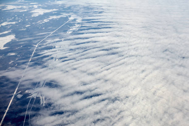 istock Aerial view from airplane window over clouds top to snow covered rivers, fields and roads 1447108411