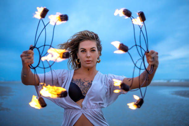 istock Beautiful female fire dancer on the beach at dusk 1447113612