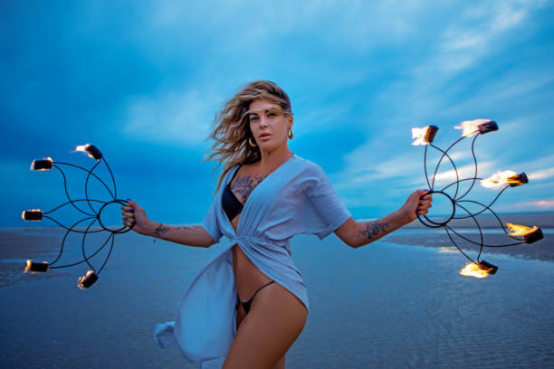 istock Beautiful female fire dancer on the beach at dusk 1447113616