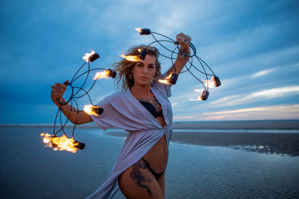 istock Beautiful female fire dancer on the beach at dusk 1447113736