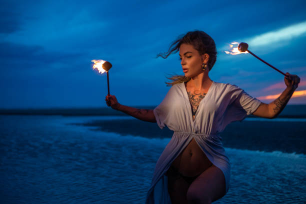 istock Beautiful female fire dancer on the beach at night 1447114701