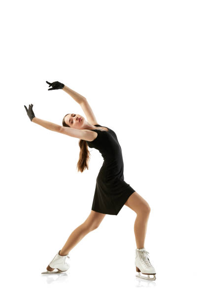 retrato de una joven flexible, patinadora artística femenina con traje de escenario negro patinando aislada sobre fondo blanco. atleta junior en movimiento. deporte, belleza, deportes de invierno - axel fotografías e imágenes de stock
