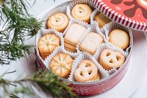 Danish Butter Cookies in Christmas Tin Box in Minimal Bright Scene with Pine tree