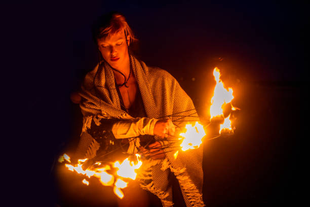 Beautiful brunette female fire dancer on the beach at night