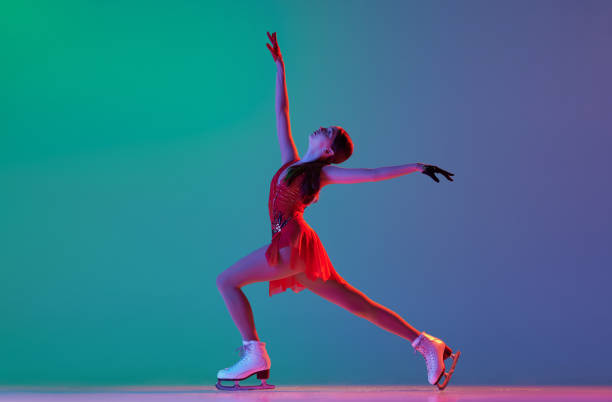 winter sports. one junior female figure skater in red stage costume showing base figure skating elements, movements isolated over gradient green-blue background in neon light. - axel imagens e fotografias de stock