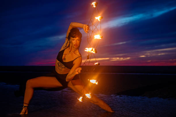 istock Beautiful brunette female fire dancer on the beach at night 1447114988
