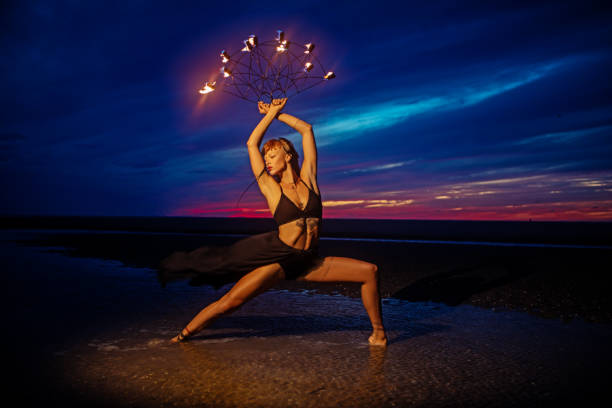 Beautiful brunette female fire dancer on the beach at night