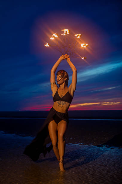 istock Beautiful brunette female fire dancer on the beach at night 1447115096