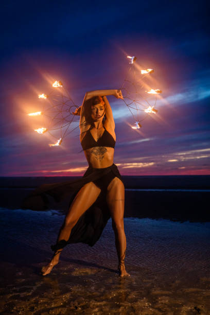 istock Beautiful brunette female fire dancer on the beach at night 1447115109