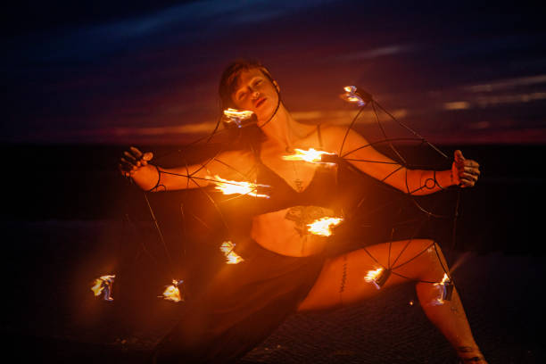 istock Beautiful brunette female fire dancer on the beach at night 1447115267