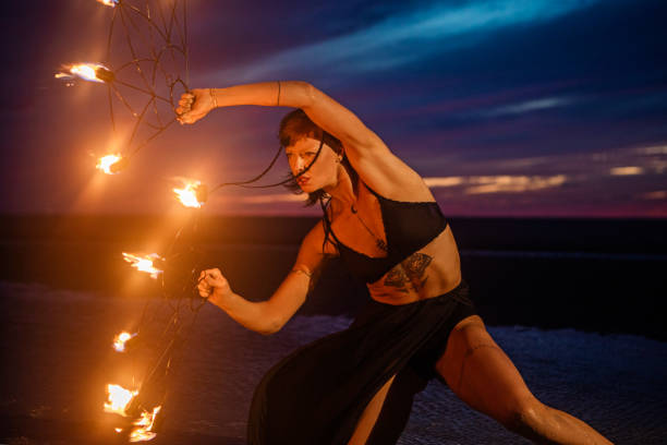 istock Beautiful brunette female fire dancer on the beach at night 1447115289