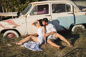 Guy and girl sitting near a rusty old car