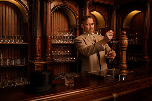 A handsome elegant 1920s style gentleman in a luxury brown bar