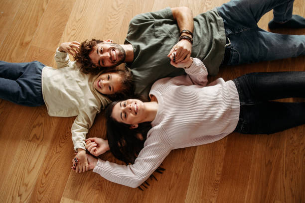 famiglia felice con una bambina sdraiata sul pavimento - floor two parent family couple home interior foto e immagini stock