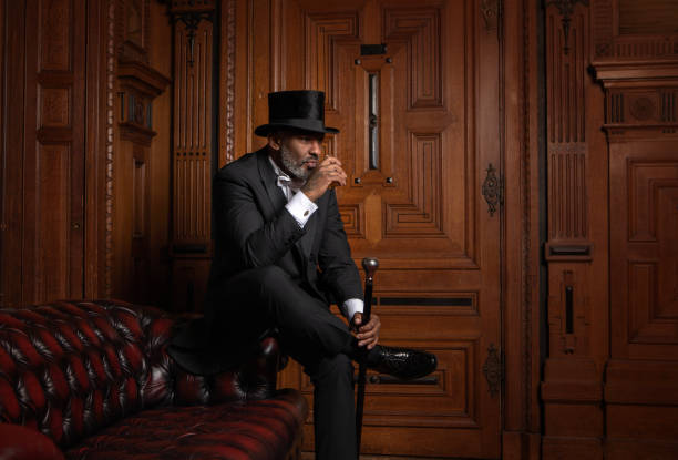 A handsome elegant 1920s style black gentleman in a luxury drawing room with a chesterfield sofa