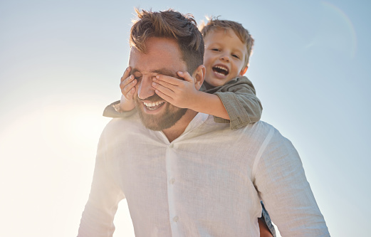 Happy family, father and child hands covering dads eyes at a beach in summer, playing and having fun with surprise, guess and game. Family, hand and kid closing father eye while walking on vacation