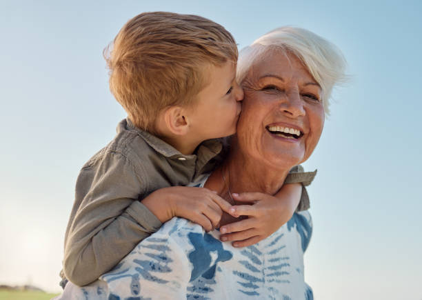 Kiss, child and grandmother in a park with love, care and freedom for happiness in retirement. Senior, smile and portrait of a woman with hug from a kid and kissing in nature or park with piggyback Kiss, child and grandmother in a park with love, care and freedom for happiness in retirement. Senior, smile and portrait of a woman with hug from a kid and kissing in nature or park with piggyback young grandparents stock pictures, royalty-free photos & images