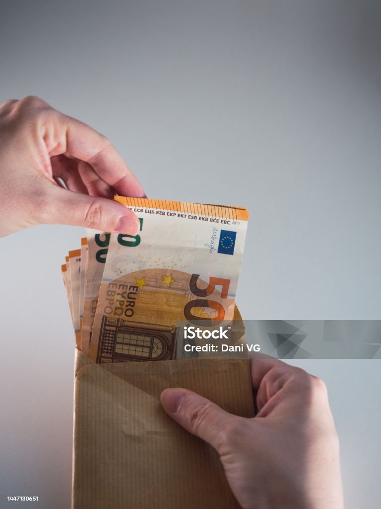 Woman's hand taking out bribe money in an envelope Bribe inside an envelope with hands tasting the money Currency Stock Photo