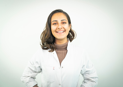 Portrait of female doctor smiling over white background. Confident healthcare worker is wearing lab coat in studio. Professional is with stethoscope.