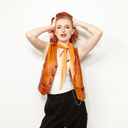 Studio portrait of a young red-haired white woman dressed in retro style against a white background