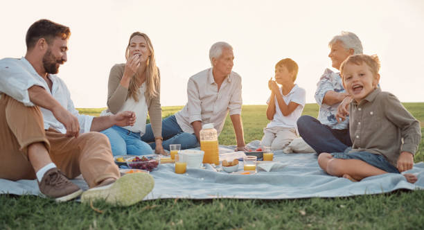 liebe, picknick und familienglück mit menschen lächeln und entspannen sich in einem park oder feld, verbinden sich und haben spaß. glückliche kinder genießen wochenendurlaub bei großeltern und eltern, liebe und essen in deutschland - senior adult old young adult couple stock-fotos und bilder