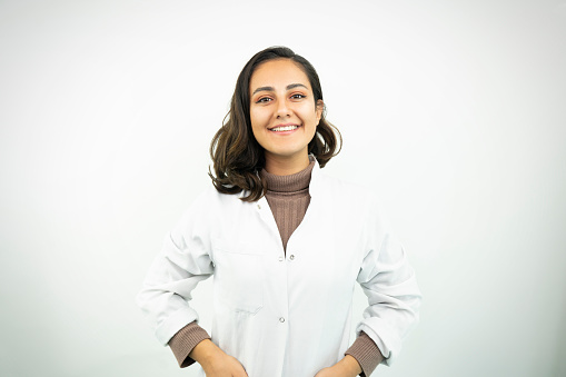 Portrait of female doctor smiling over white background. Confident healthcare worker is wearing lab coat in studio. Professional is with stethoscope.