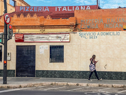 Valencia, Spain - December 1, 2022: Woman walking next to closed Italian pizza shop. The post pandemic and the high rates of inflation caused a lot of businesses to bankrupt