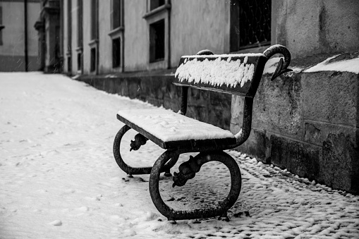 Abandoned street bench covered by snow in winter time. Cold winter days in Prague, Czech Republic