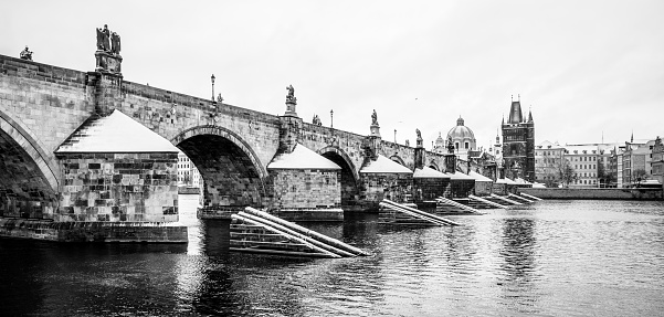 Historical Charles Bridge, Czech: Karluv most, over Vltava River in winter. Prague, Czech Republic. Black and white image.