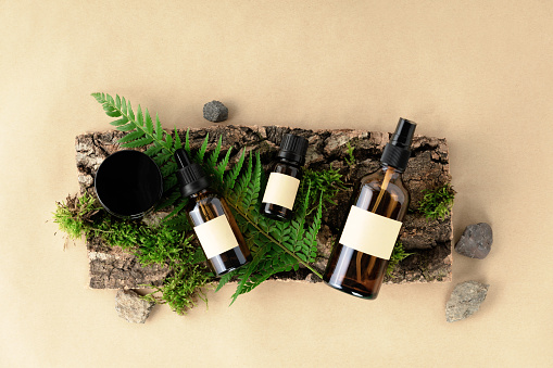 Unlabelled cosmetic bottles on natural beige background, natural moss over branches, bark. Skin care, organic body treatment, spa concept. Vegan eco friendly cosmetology product. Organic cosmetics