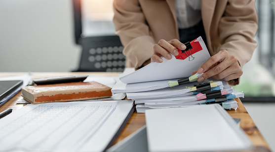 Businesswoman hands working on Stacks paper document files on her desk.