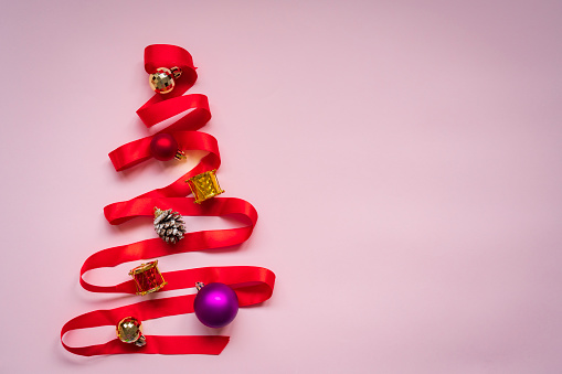 Christmas Tree with red ribbon on pink background