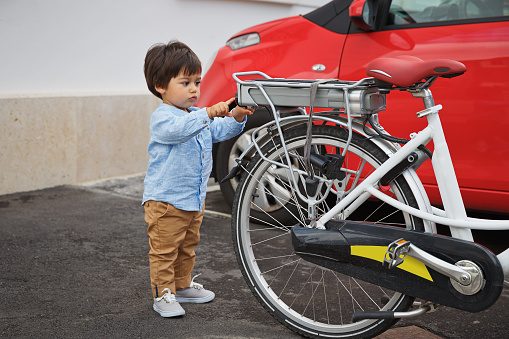 Portrait of a little eastern handsome baby boy playing outdoor with a bicycle. Arabian child fun on the street.