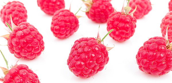 Background of fresh garden raspberries scattered on a white background.