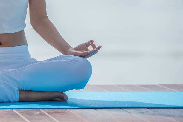 frau im weißen yogaanzug sitzt morgens meditierend am see. - zen like meditating yoga business stock-fotos und bilder