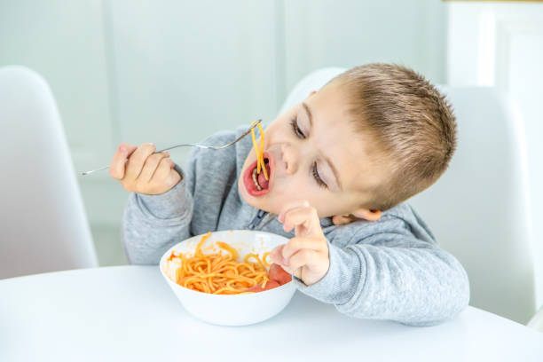 istock children in the kitchen at the table turning pasta. 1447151813